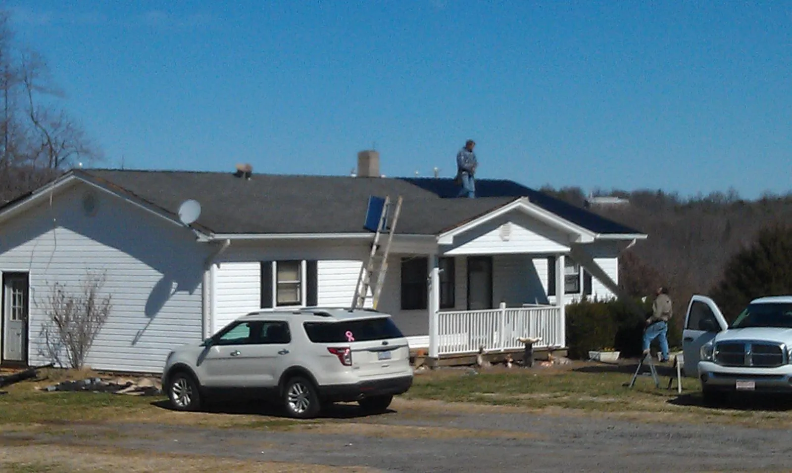 Roofers stripping shingles from a white ranch house roof in Norwalk